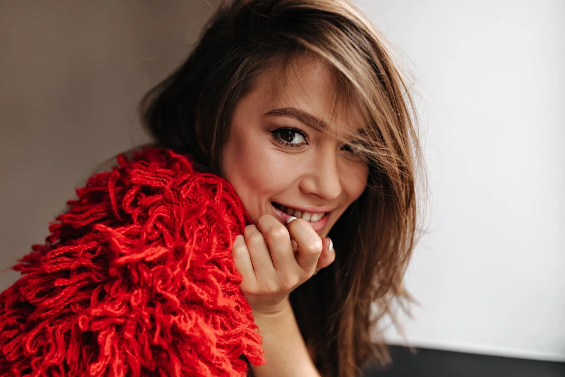 cute-browneyed-woman-knitted-red-outfit-playfully-looking-camera-with-smile-white-background